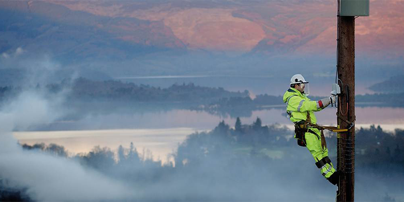 Image of engineer climbing pole with Scottish landscape in the background