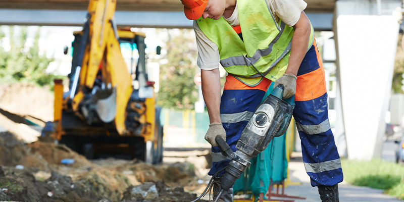 Construction worker with perforator digging in street