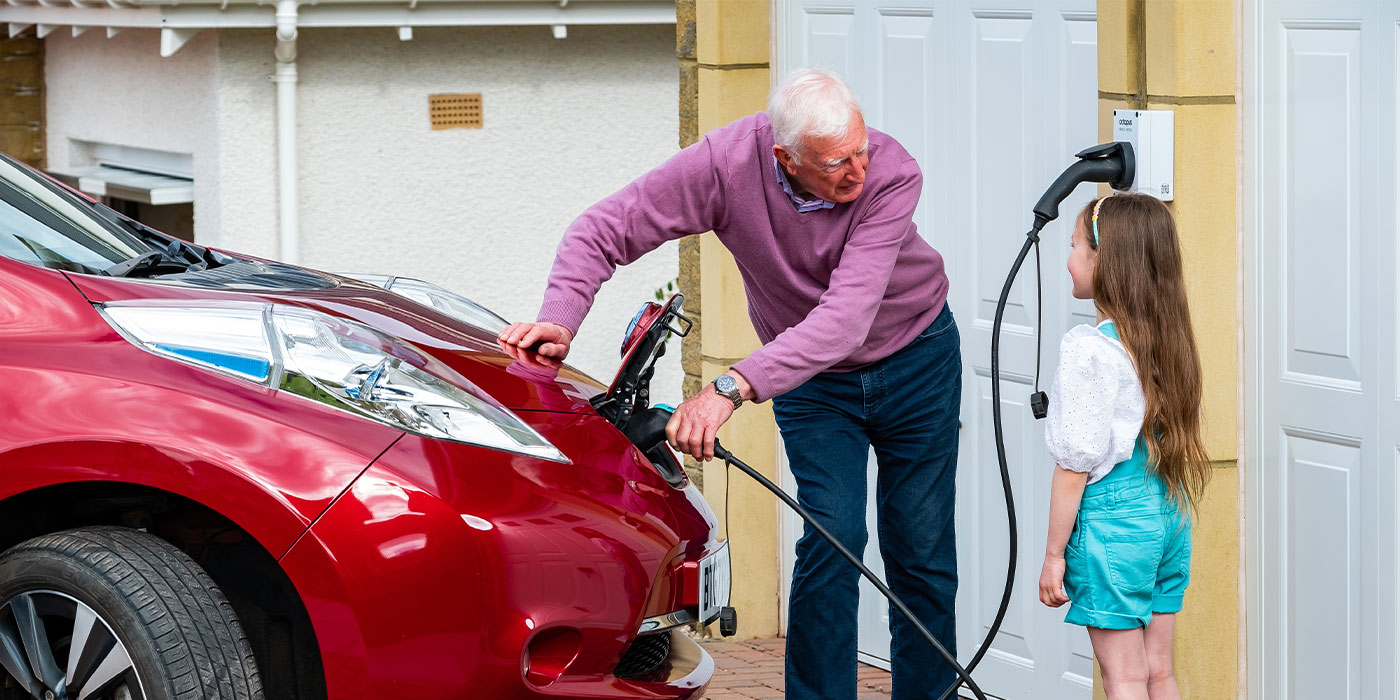 man charging ev talking to little girl